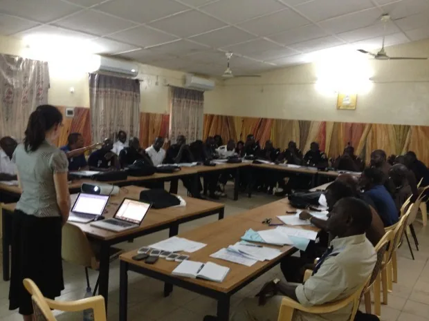 Classroom training session in Senegal, with more than thirty Service National de l'Hygiène agents seated at tables facing a trainer and two laptops