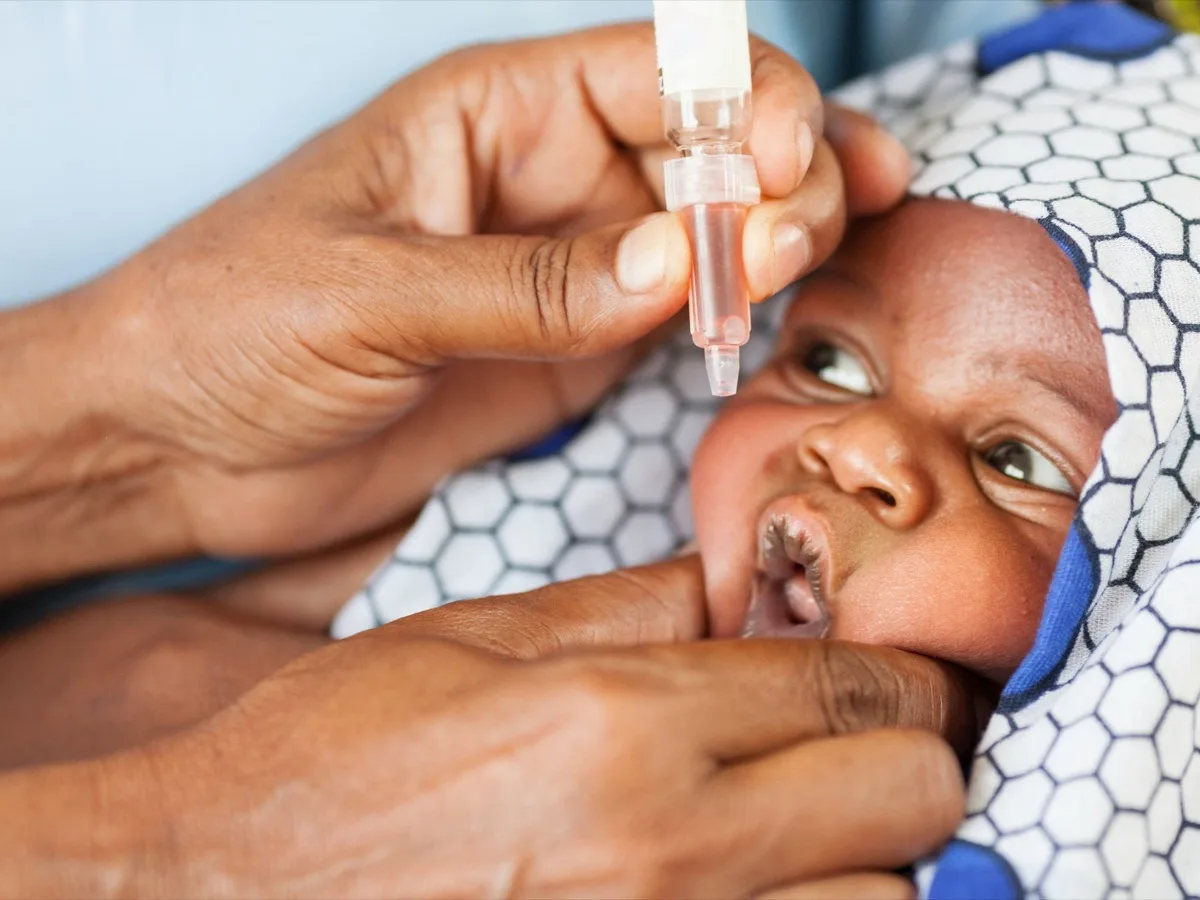 A health worker administers drops of oral polio vaccine to an infant