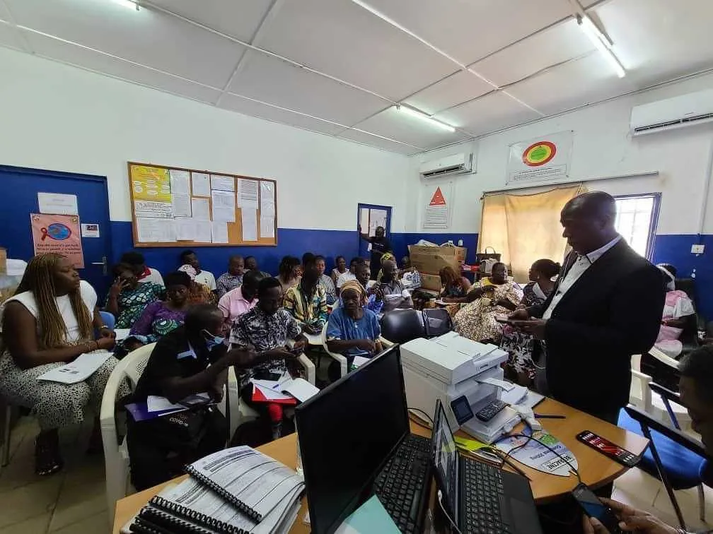 Campaign administrators and health workers gather in a room during an enrollment and payment session