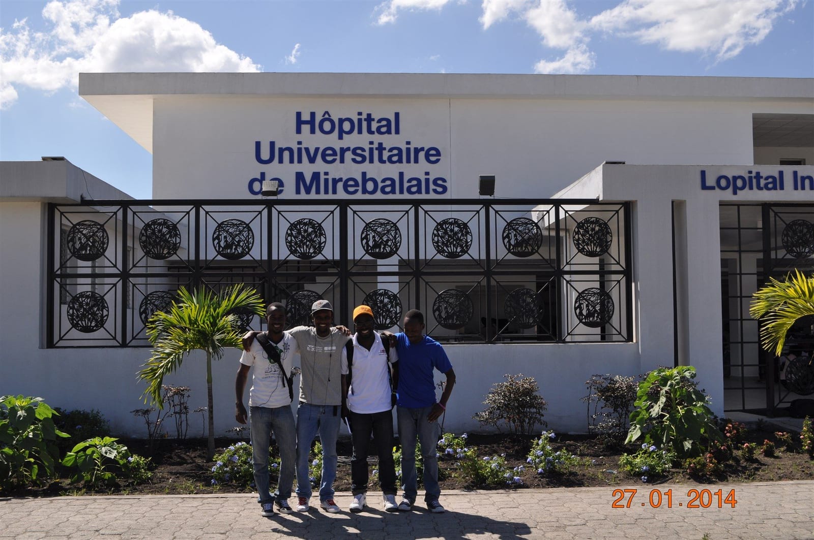 A group of students standing outside the entrance of Hopital Universitaire de Mirebalais in Haiti