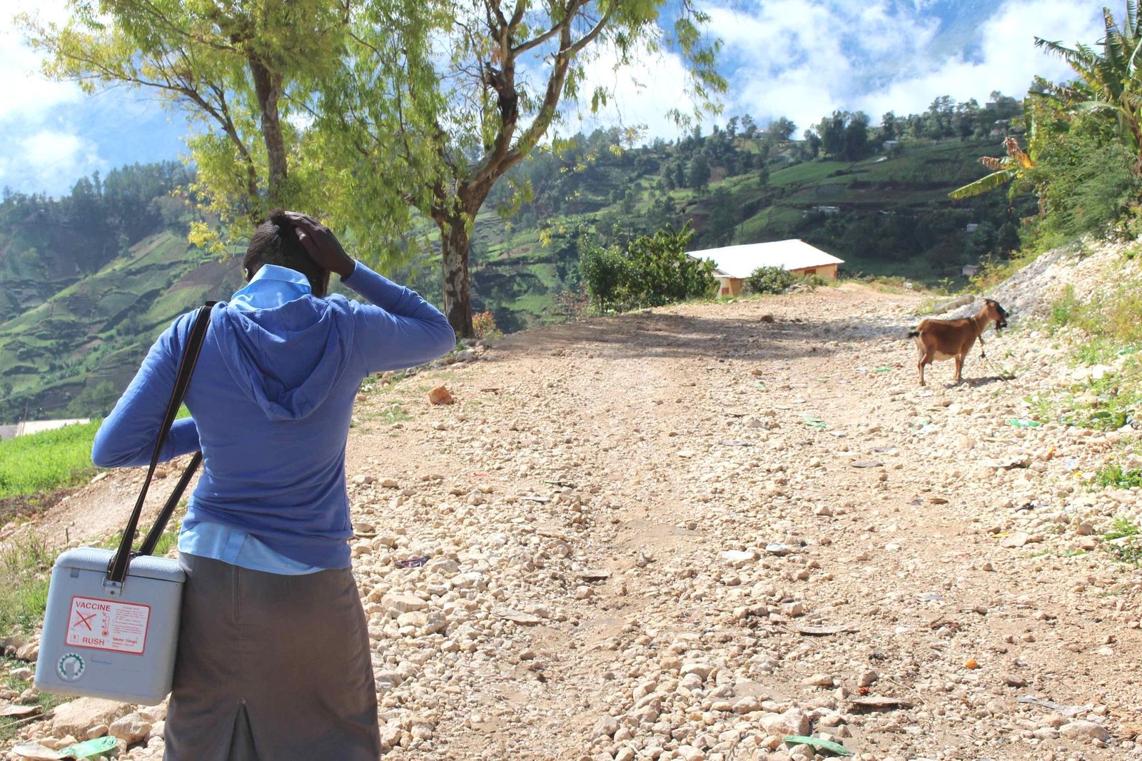 Ketcia Ovillus moves onto her last home visit carrying vaccinations for children in a gray thermal box