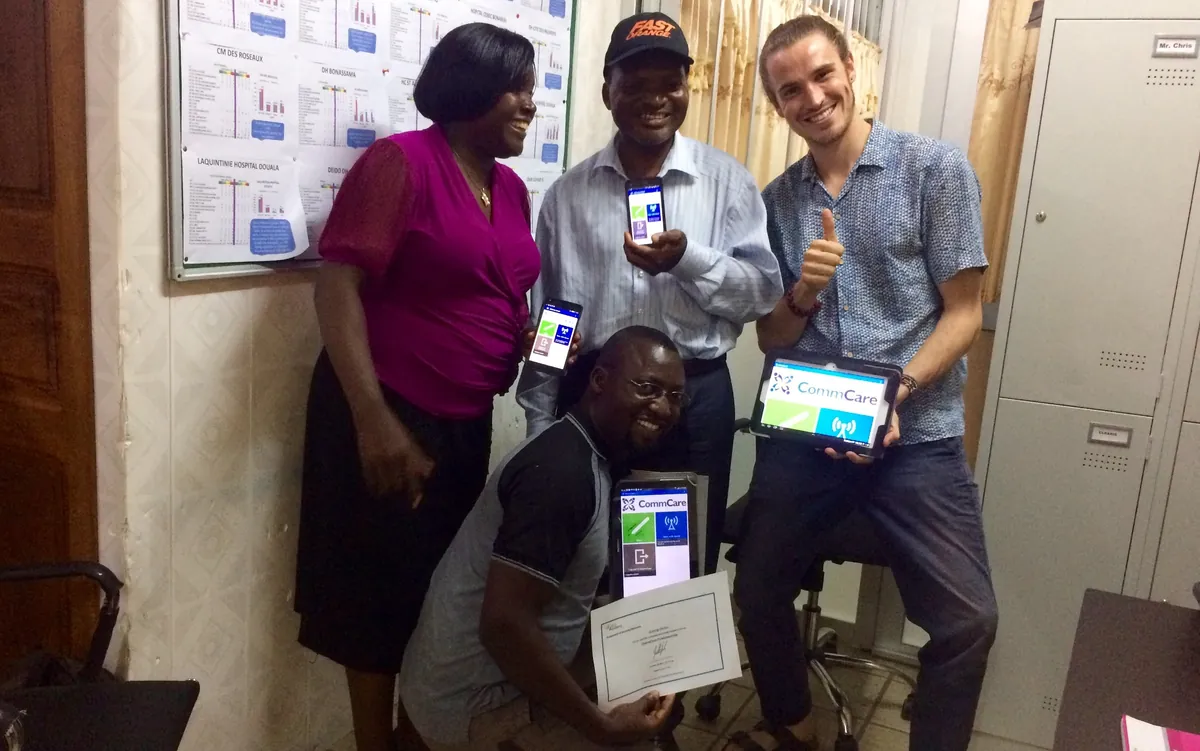 Four members of the health team smiling and holding Android phones and a tablet running CommCare, one kneeling with a CommCare certificate